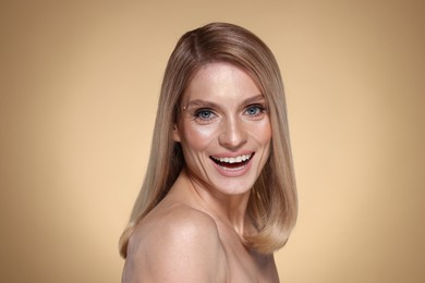 Photo of Portrait of beautiful happy woman with straight blonde hair on beige background