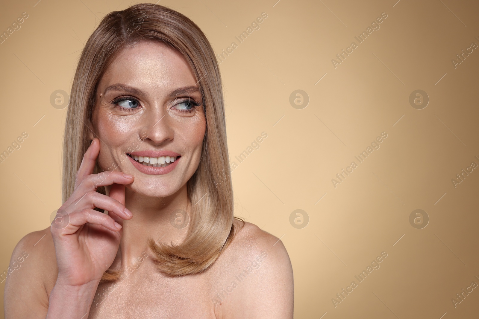 Photo of Portrait of beautiful happy woman with straight blonde hair on beige background, space for text