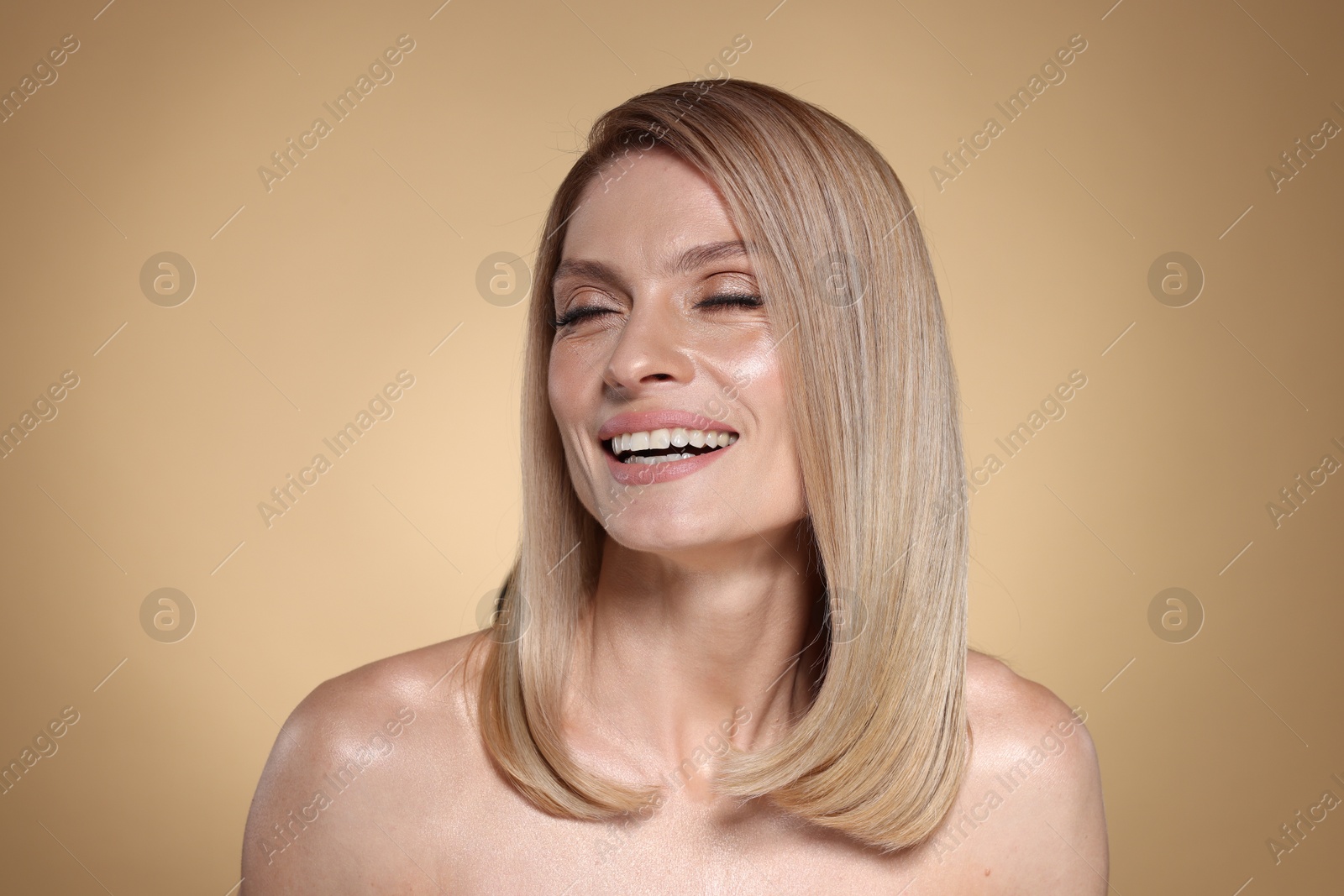 Photo of Portrait of beautiful happy woman with straight blonde hair on beige background