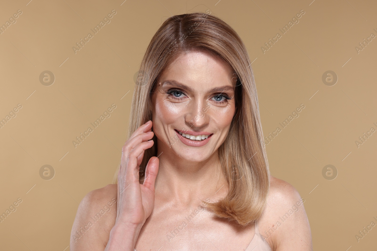 Photo of Portrait of beautiful happy woman with straight blonde hair on beige background