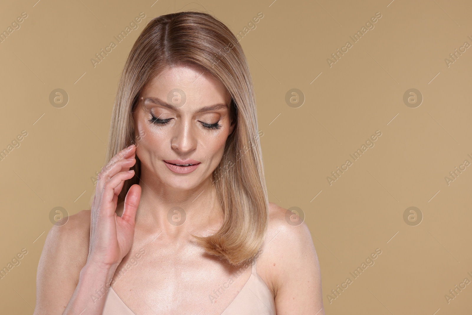 Photo of Beautiful woman with straight blonde hair and stylish makeup on beige background