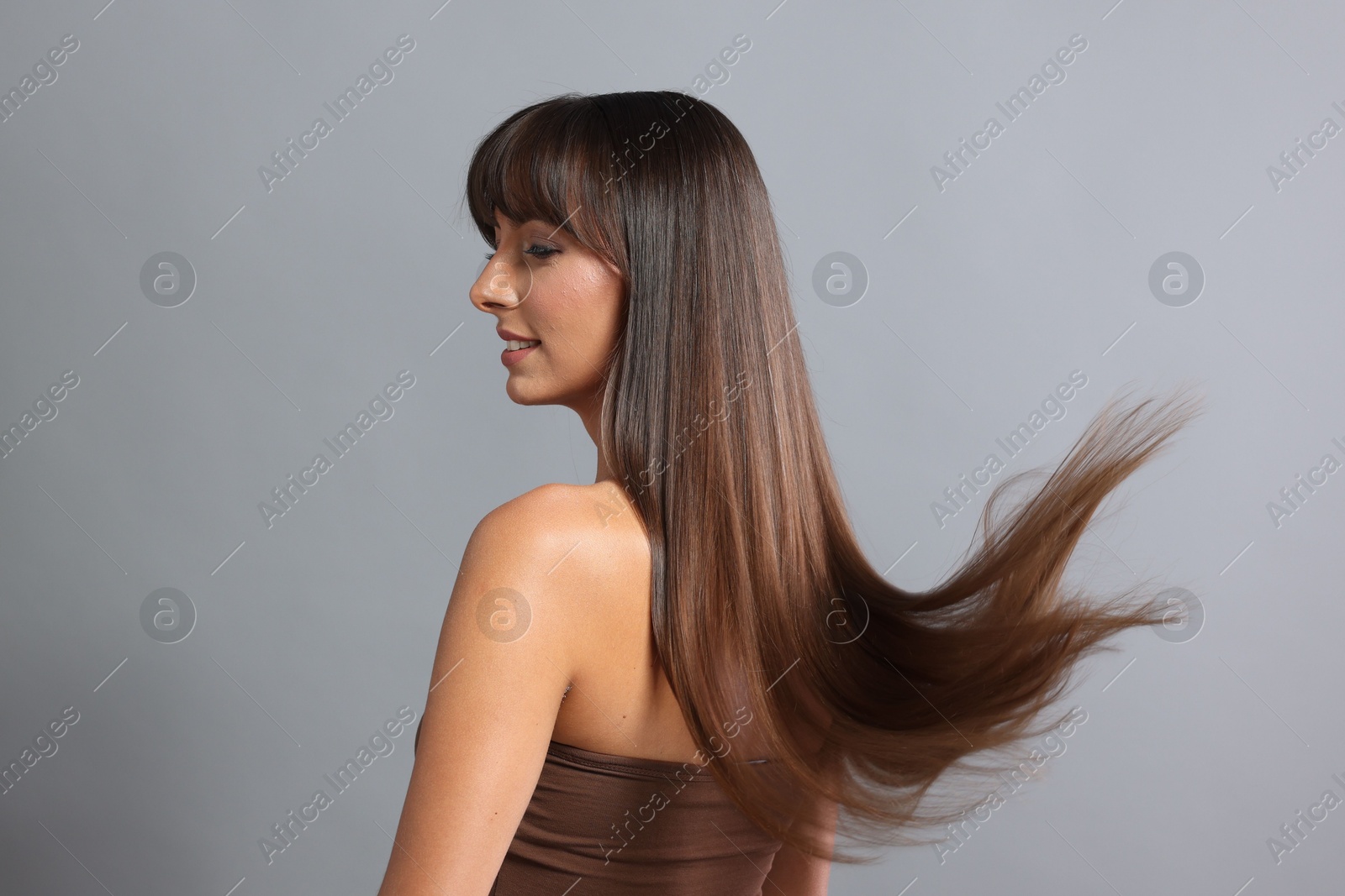 Photo of Hair styling. Beautiful woman with straight long hair on grey background