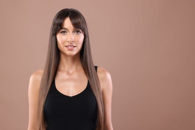 Photo of Hair styling. Portrait of beautiful woman with straight long hair on pale brown background