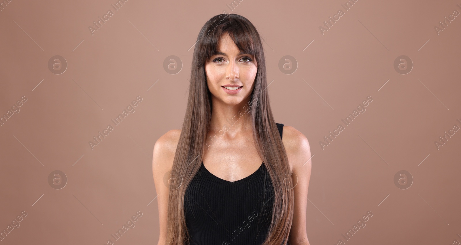 Photo of Hair styling. Portrait of beautiful woman with straight long hair on pale brown background