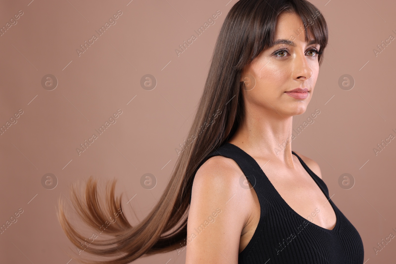 Photo of Hair styling. Beautiful woman with straight long hair on pale brown background, space for text