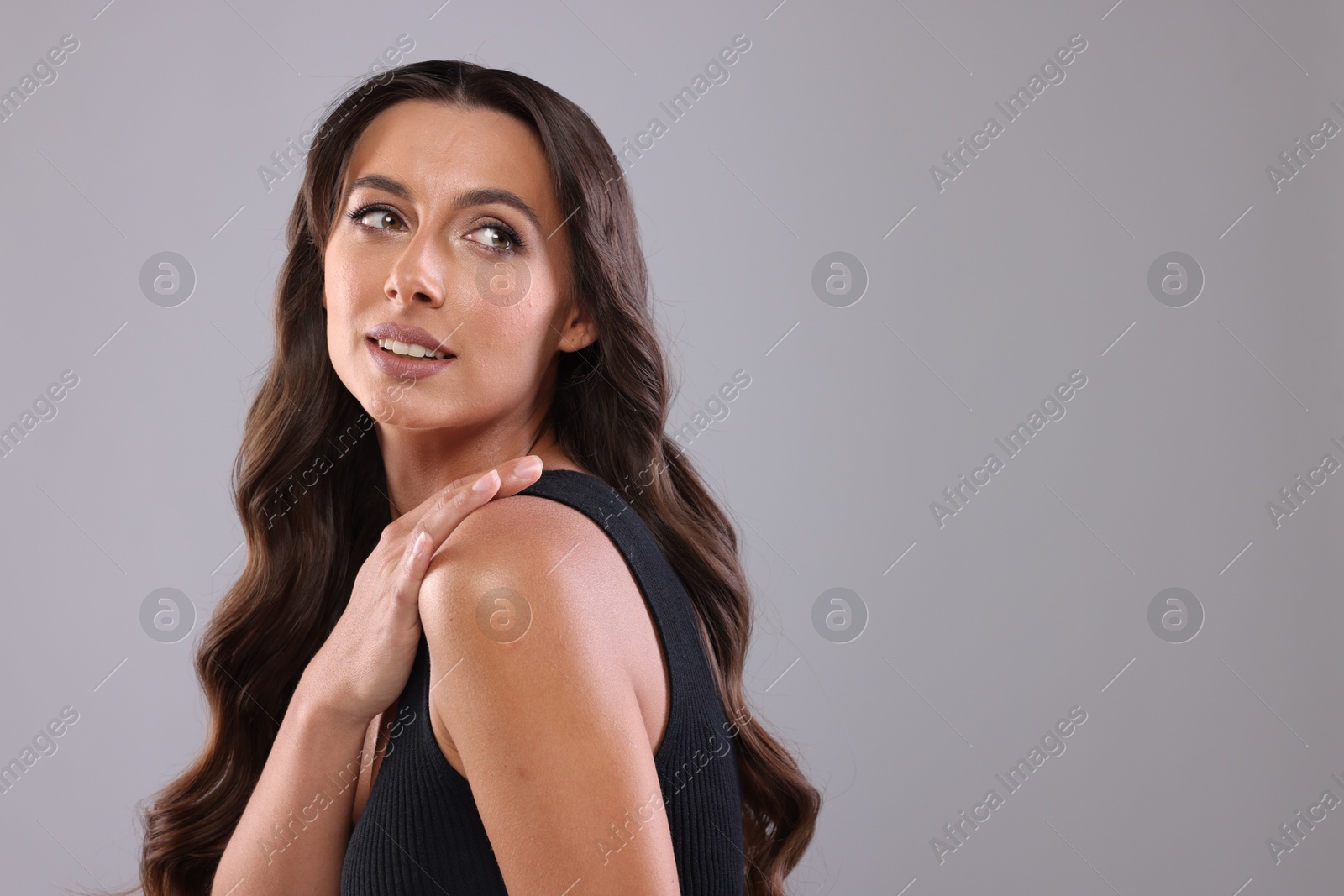 Photo of Hair styling. Beautiful woman with wavy long hair on grey background, space for text