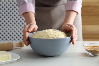 Photo of Making cinnamon rolls. Woman with dough at white wooden table, closeup