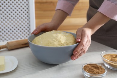 Photo of Making cinnamon rolls. Woman with dough at white wooden table, closeup