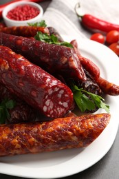 Photo of Different smoked sausages and parsley on grey table, closeup