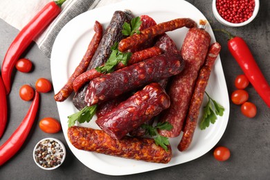 Photo of Flat lay composition with different smoked sausages and peppercorns on grey textured table