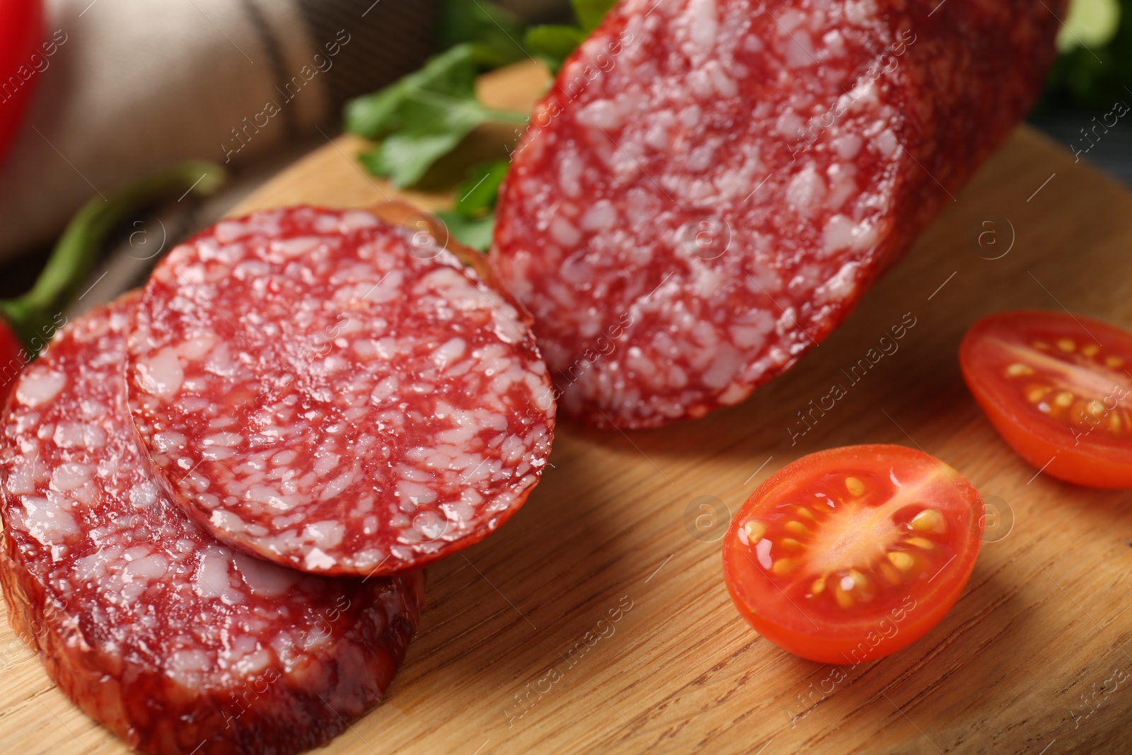 Photo of Cut smoked sausage and tomato on wooden board, closeup