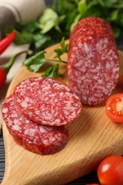 Photo of Cut smoked sausage, parsley and tomatoes on black wooden table, closeup