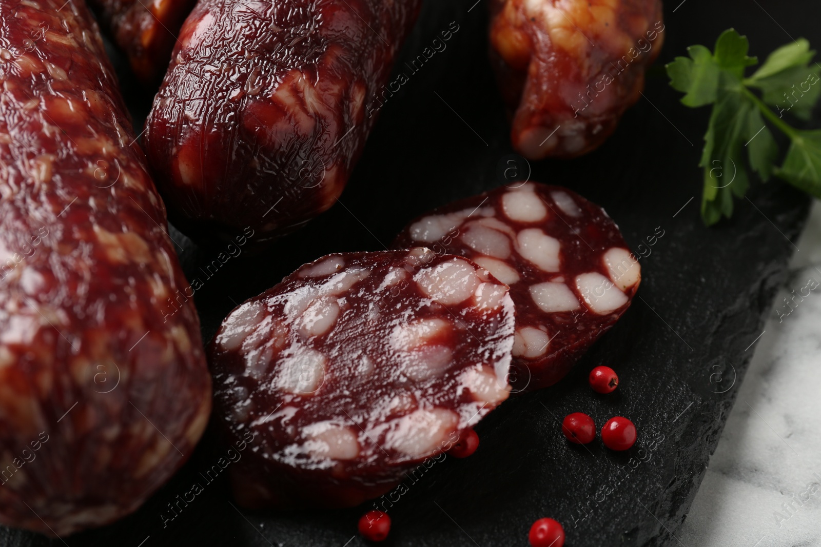 Photo of Different smoked sausages and peppercorns on light table, closeup