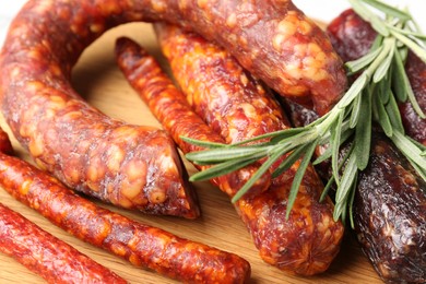 Photo of Different smoked sausages and rosemary on wooden board, closeup