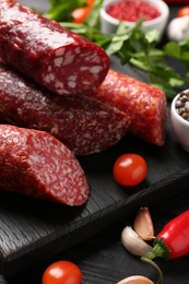 Photo of Different smoked sausages and products on black wooden table, closeup