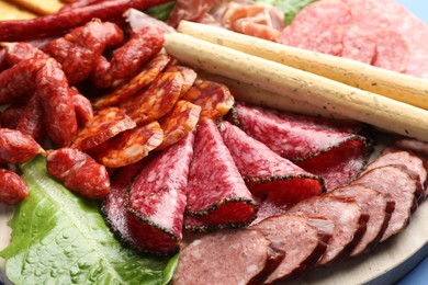 Photo of Different smoked sausages and other snacks on board, closeup