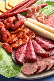 Photo of Different smoked sausages and other snacks on table, closeup