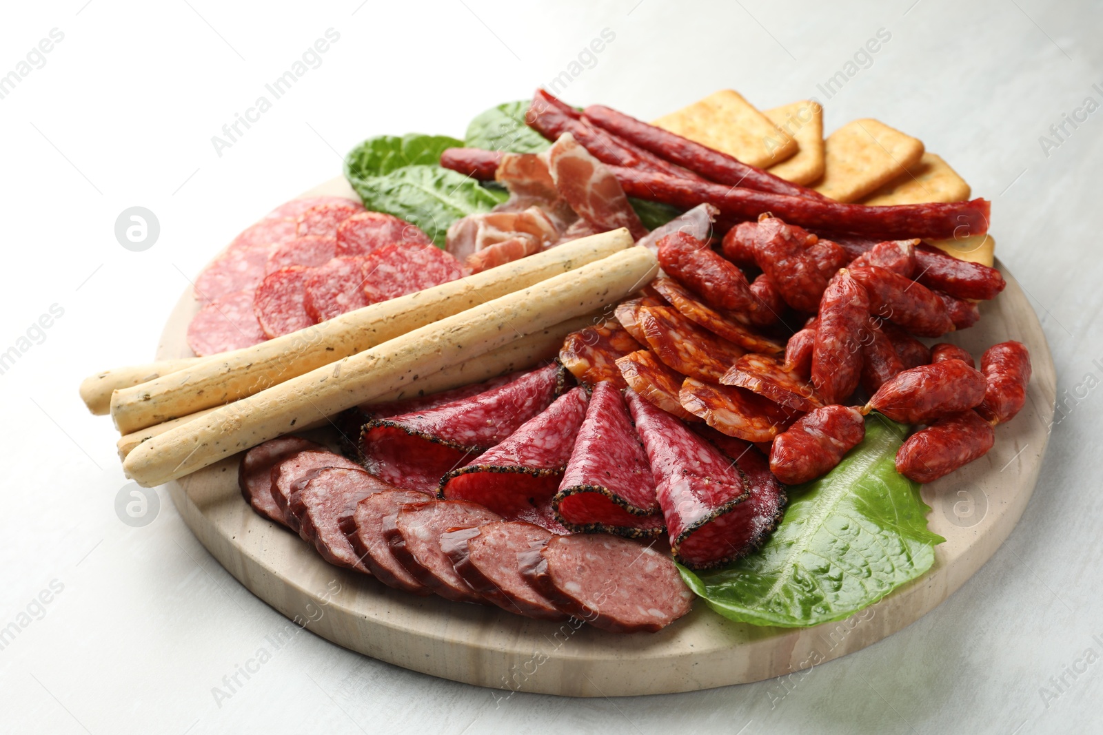 Photo of Different smoked sausages and other snacks on white table, closeup