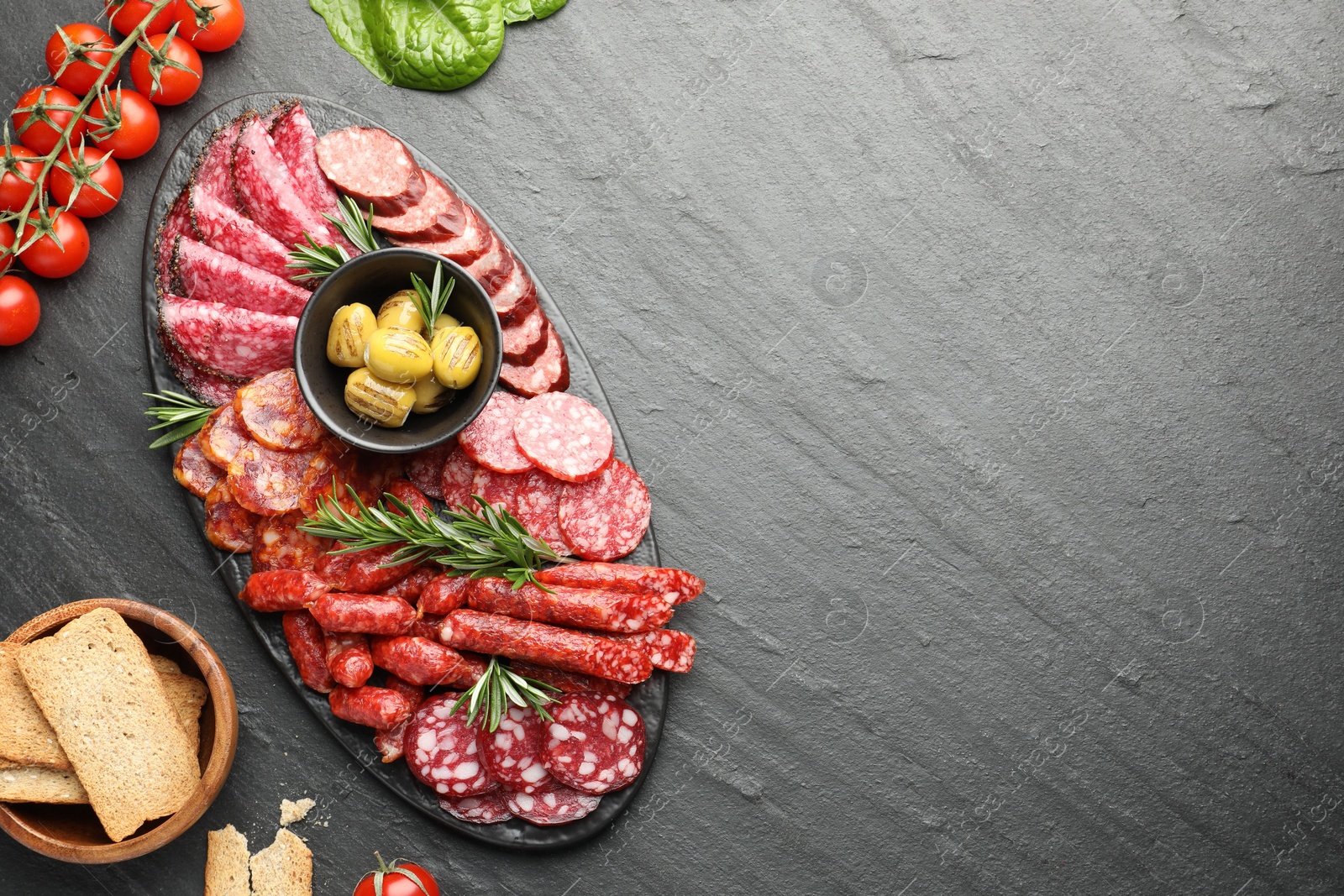 Photo of Different smoked sausages and other snacks on black table, flat lay. Space for text