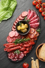 Photo of Different smoked sausages and other snacks on black table, flat lay