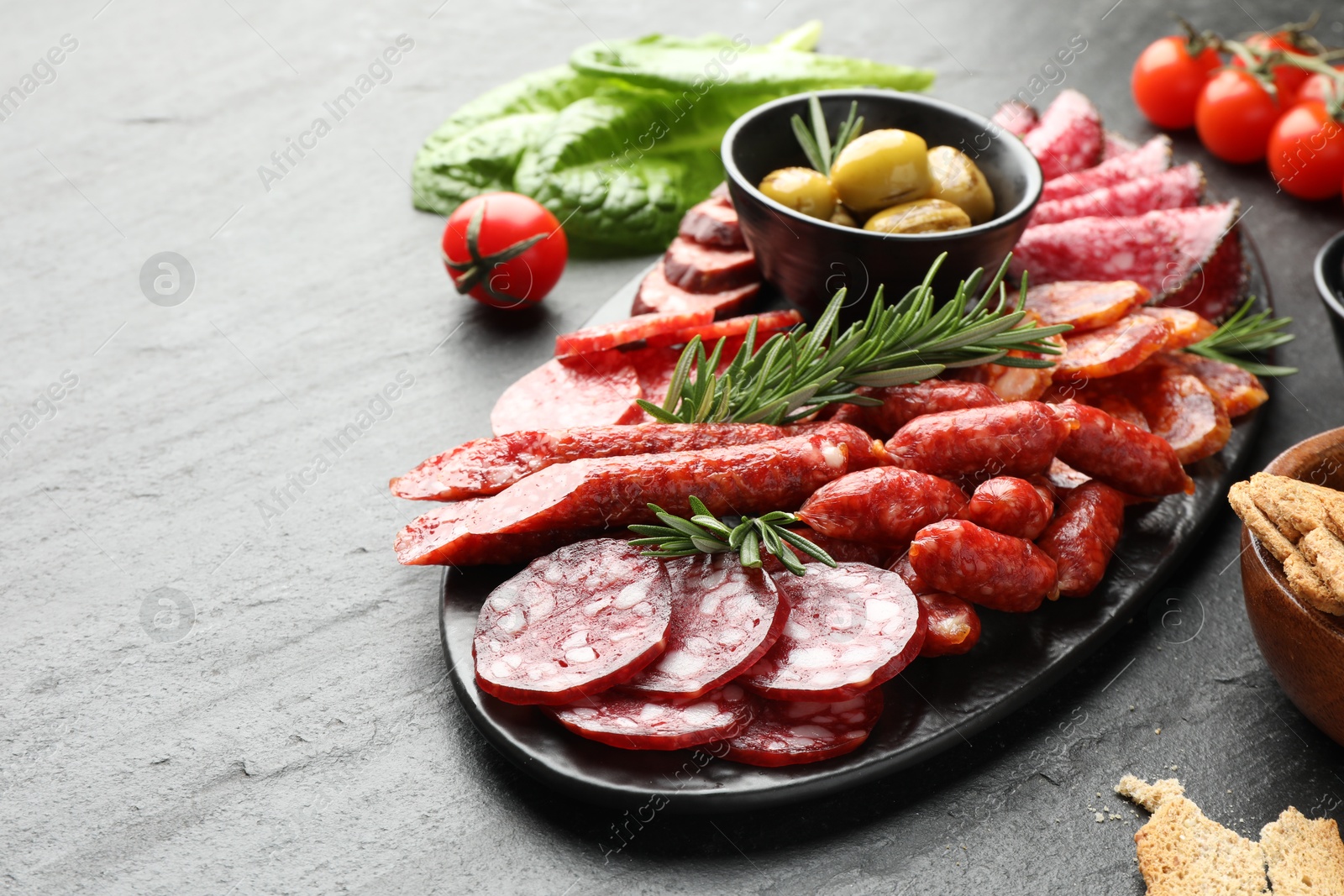 Photo of Different smoked sausages and other snacks on black table, closeup. Space for text