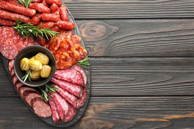 Photo of Different smoked sausages, olives and rosemary on wooden table, top view. Space for text