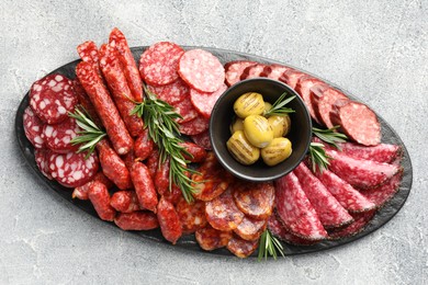 Photo of Different smoked sausages, olives and rosemary on grey table, top view