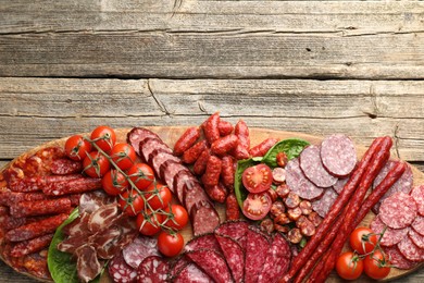 Photo of Different smoked sausages, ham and tomatoes on wooden table, top view. Space for text