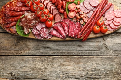 Photo of Different smoked sausages, ham and tomatoes on wooden table, top view. Space for text