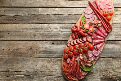 Photo of Different smoked sausages, ham and tomatoes on wooden table, top view. Space for text