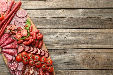 Photo of Different smoked sausages, ham and tomatoes on wooden table, top view. Space for text