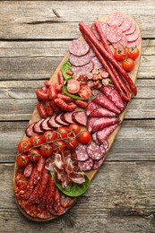 Photo of Different smoked sausages, ham and tomatoes on wooden table, top view