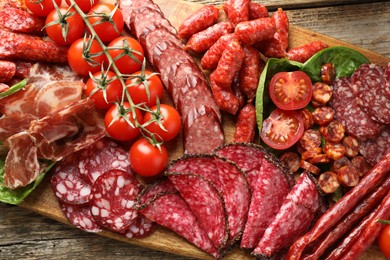 Photo of Different smoked sausages, ham and tomatoes on wooden table, top view