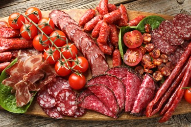 Photo of Different smoked sausages, ham and tomatoes on wooden table, top view