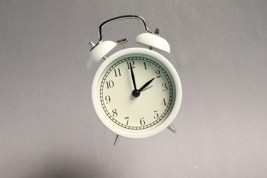 Photo of White alarm clock in air on light grey background