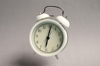 Photo of White alarm clock in air on light grey background