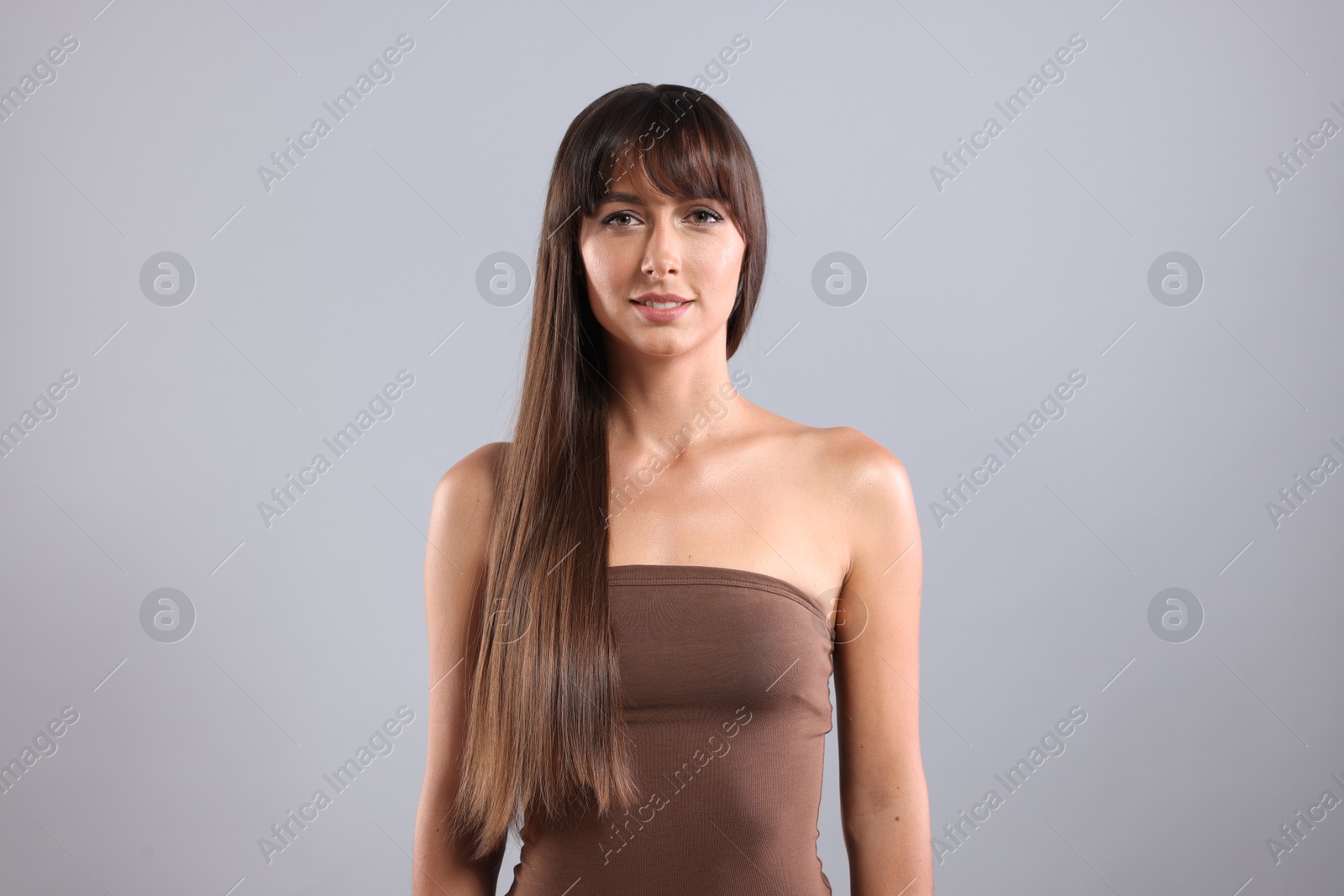 Photo of Hair styling. Portrait of beautiful woman with straight long hair on grey background