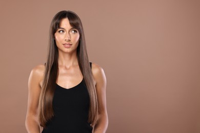 Photo of Hair styling. Beautiful woman with straight long hair on pale brown background, space for text