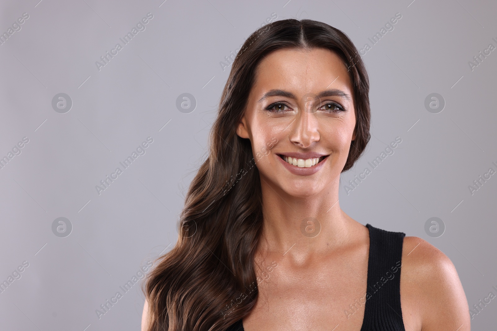 Photo of Hair styling. Portrait of beautiful woman with wavy long hair on grey background