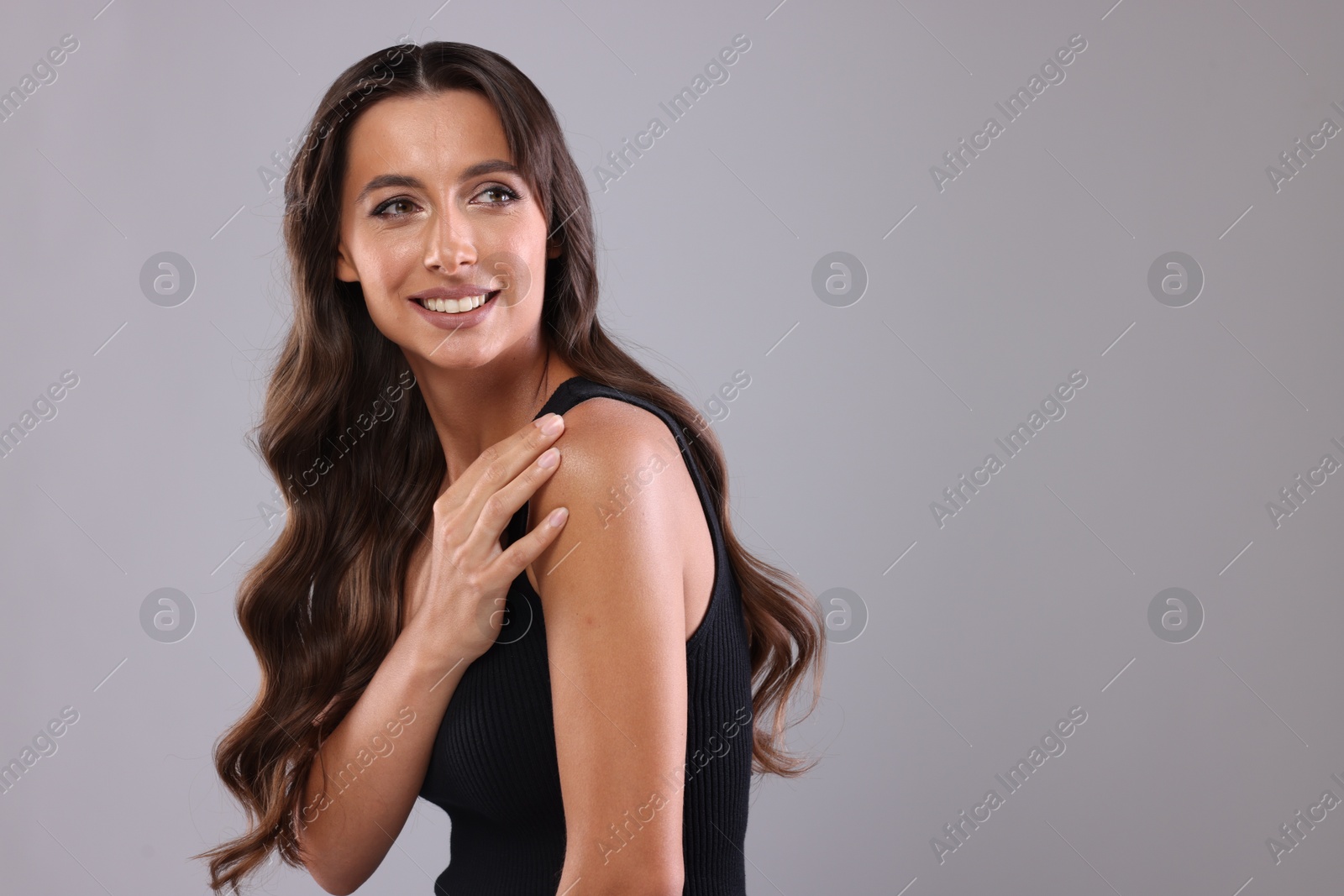 Photo of Hair styling. Beautiful woman with wavy long hair on grey background, space for text