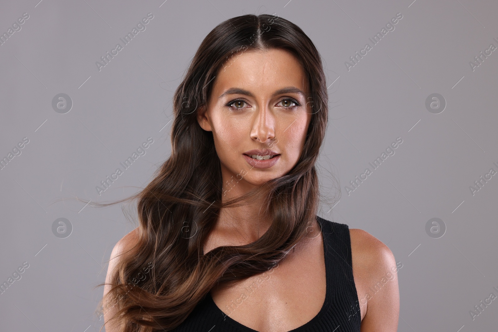 Photo of Hair styling. Portrait of beautiful woman with wavy long hair on grey background, space for text