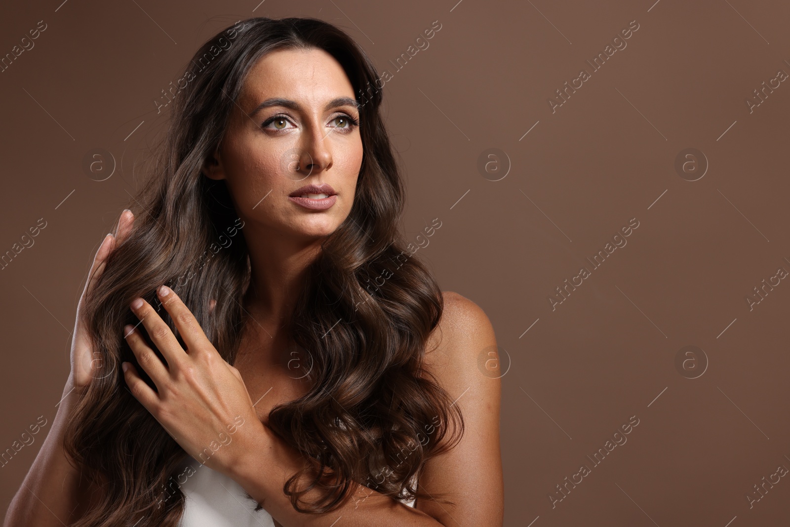 Photo of Hair styling. Beautiful woman with wavy long hair on brown background, space for text