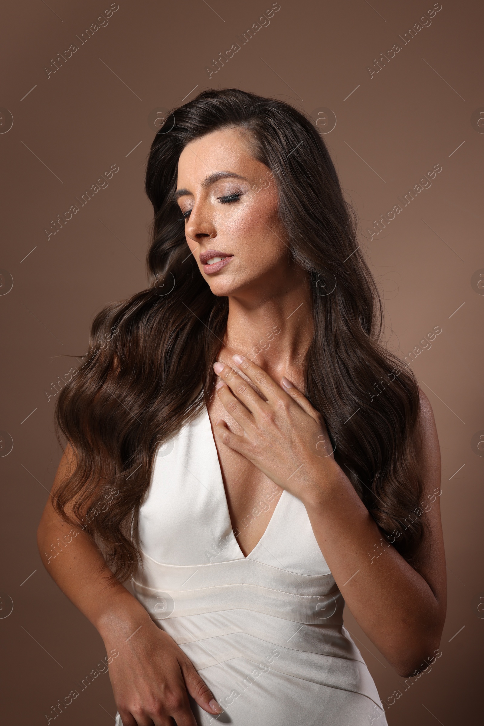 Photo of Hair styling. Beautiful woman with wavy long hair on brown background