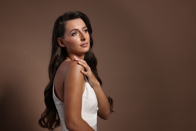 Photo of Hair styling. Beautiful woman with wavy long hair on brown background, space for text