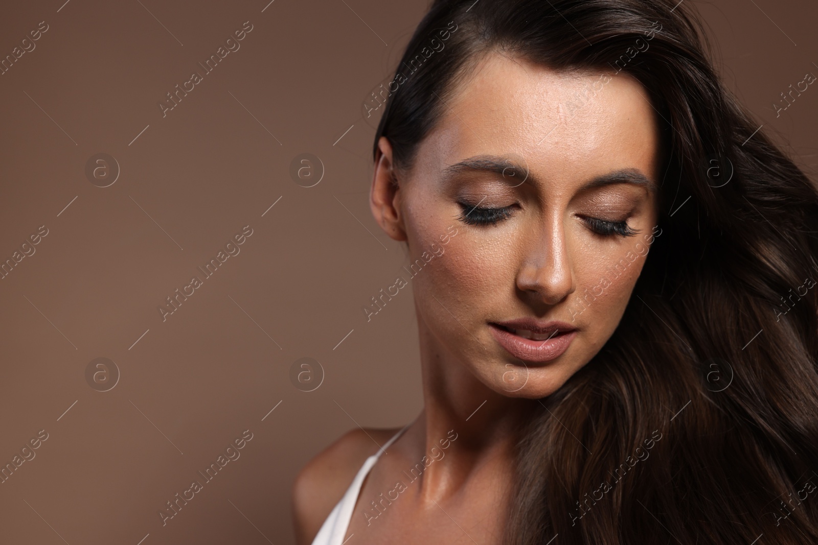 Photo of Hair styling. Beautiful woman with wavy long hair on brown background, space for text