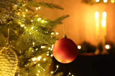 Photo of Christmas tree decorated with bauble and festive lights indoors, closeup