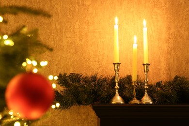 Christmas tree decorated with bauble, festive lights, burning candles and garland indoors, selective focus