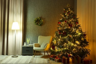 Photo of Cozy room with beautiful Christmas tree, armchair and lamp. Interior design for holiday