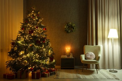 Photo of Cozy room with beautiful Christmas tree, armchair and lamp. Interior design for holiday