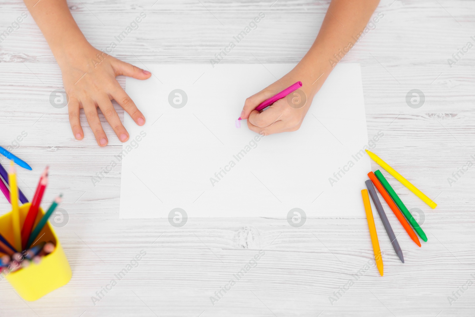 Photo of Boy drawing picture at light wooden table, top view